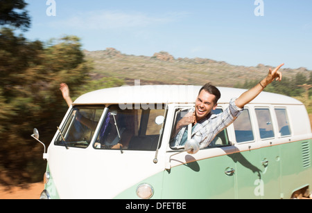Man leaning head out camper van window on rural road Stock Photo
