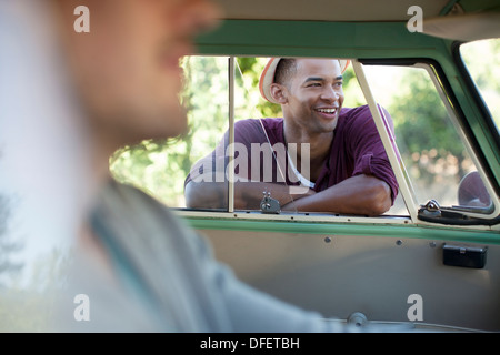 Smiling man standing at camper van window Stock Photo