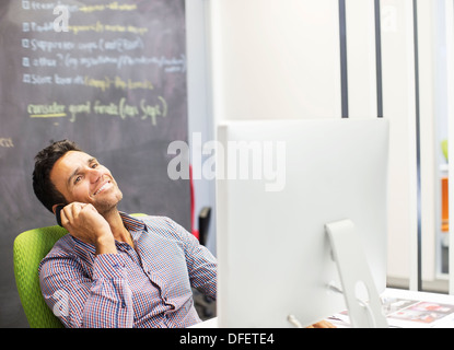 Businessman talking on cell phone at desk in office Stock Photo