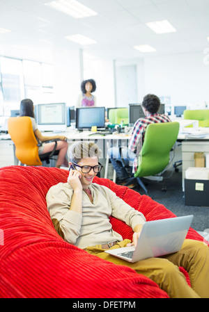 Businessman working in beanbag chair in office Stock Photo