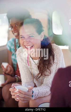 Women drinking coffee in back seat of van Stock Photo