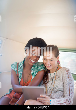 Women using digital tablet in back seat of camper van Stock Photo