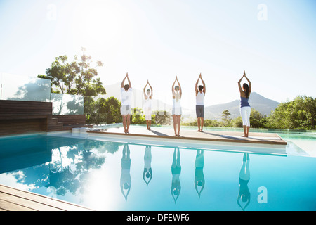 People practicing yoga at poolside Stock Photo