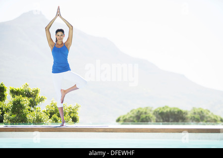 Woman practicing yoga balancing on one leg on a mat in a high key