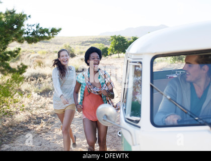 Women walking to camper van on rural road Stock Photo