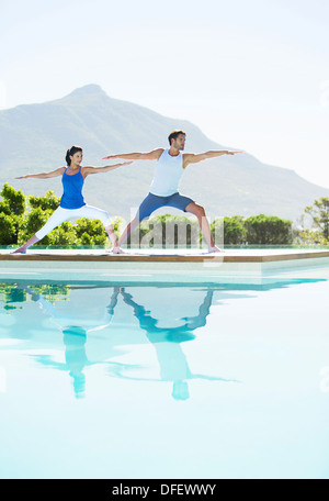 Couple practicing yoga at poolside Stock Photo