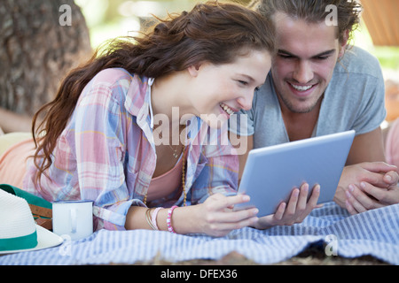 Couple using digital tablet on blanket outdoors Stock Photo