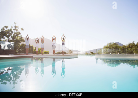 People practicing yoga at poolside Stock Photo