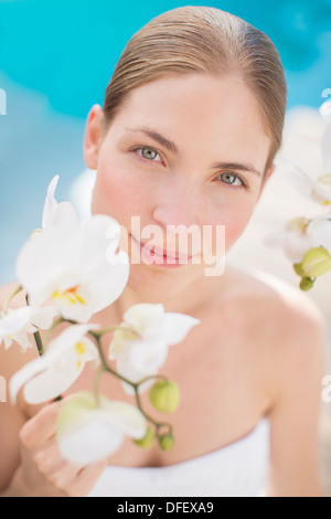 Woman holding flower poolside Stock Photo