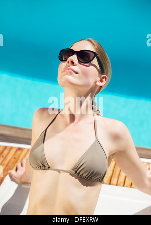 Woman sunbathing at poolside Stock Photo