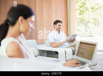 Couple using digital tablet and laptop in livingroom Stock Photo