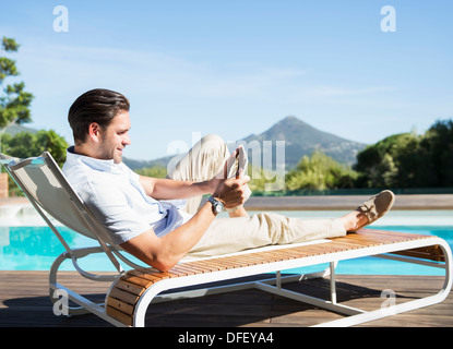 Man in camping lounge chair fishing and using digital tablet Stock Photo -  Alamy