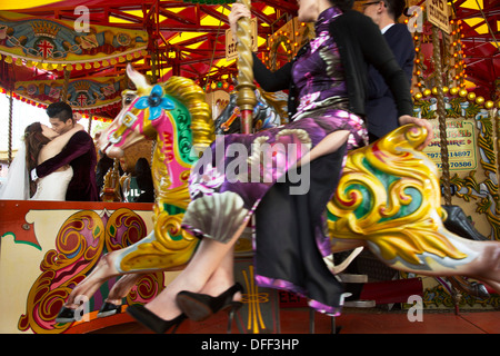Bride and groom kissing on a merry-go-round. Chinese wedding party of friends and relatives along the South Bank, London, UK. Stock Photo