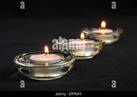 Three burning candles on black background. Stock Photo