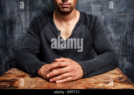 Young man is sitting at desk in front of a blackboard Stock Photo