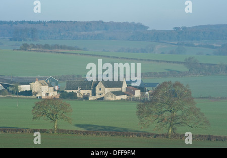 A rural scene and farm house in the Cotswolds in sunshine with clearing fog Stock Photo