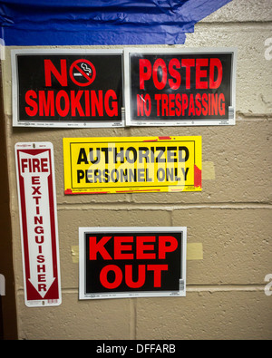 Safety reminders, no trespassing and danger signs bar entry during an asbestos remediation project Stock Photo
