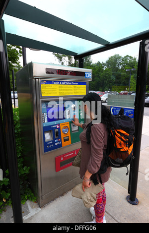 Hispanic girl buying a ticket using an automated ticket vending machine with touchscreen, Falls Road Light Rail Stop, Baltimore County, Maryland, USA Stock Photo