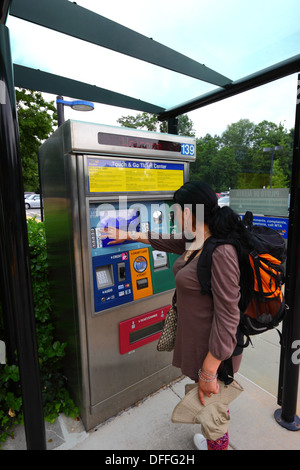 Hispanic girl buying a ticket using an automated ticket vending machine with touchscreen, Falls Road Light Rail Stop, Baltimore County, Maryland, USA Stock Photo