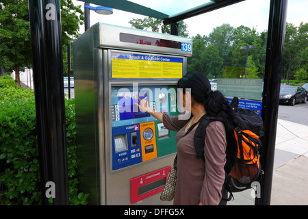 Hispanic girl buying a ticket using an automated ticket vending machine with touchscreen, Falls Road Light Rail Stop, Baltimore County, Maryland, USA Stock Photo