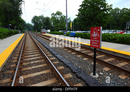 Look both ways before crossing sign next to pedestrian crossing, Falls Road Light Rail Stop, Baltimore County, Maryland, USA Stock Photo