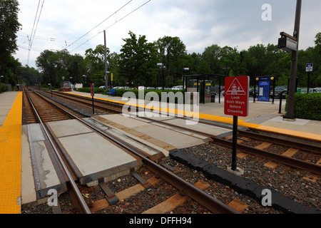 Look both ways before crossing sign next to pedestrian crossing, Falls Road Light Rail Stop, Baltimore County, Maryland, USA Stock Photo