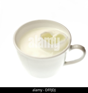 A heart made of milk splashes in a white cup on a white background Stock Photo