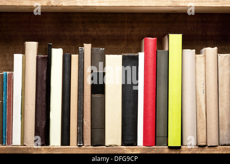 Old books on a wooden shelf. No labels, blank spine. Stock Photo