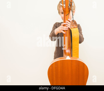 Young girl, 4 years old, playing with an acoustic guitar. Stock Photo