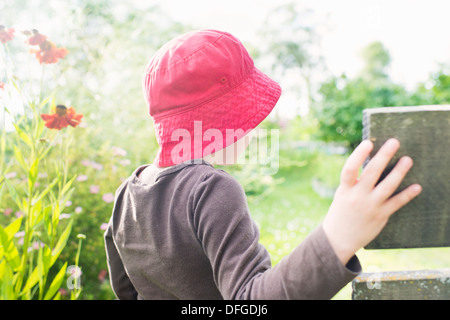 Lifestyle moment with young girl watching a garden filled with flowers and green plants Stock Photo