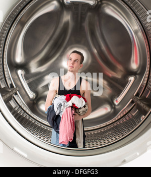 Conceptual image of young confused man holding laundry inside a washing mashine Stock Photo