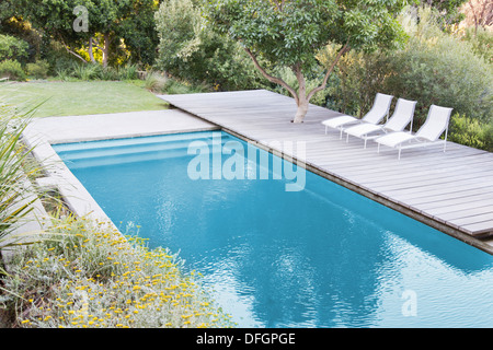 Wooden deck and lounge chairs by swimming pool Stock Photo