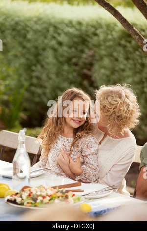 Mother and daughter sitting at table outdoors Stock Photo