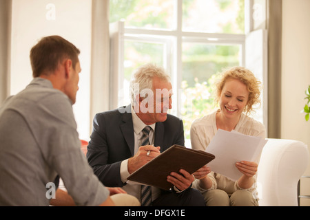 Financial advisor talking to couple in living room Stock Photo