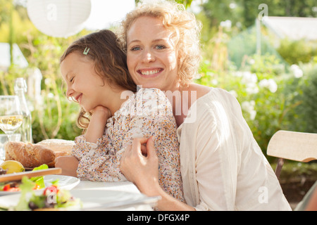 Mother and daughter smiling at table outdoors Stock Photo