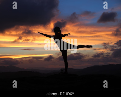 Ballet dancer in silhouette, Arabesque pose at sunset. Stock Photo