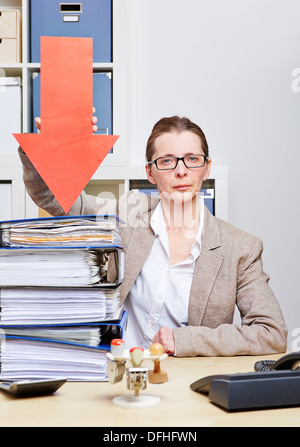 Strict business woman in her office pointing arrow to stack of files Stock Photo