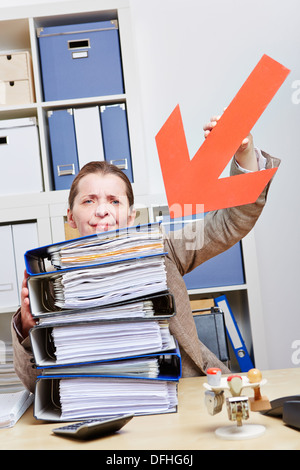 Stressed business woman pointing with arrow to stack of files Stock Photo