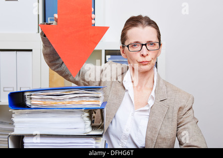 Serious business woman in her office pointing with arrow to many files Stock Photo