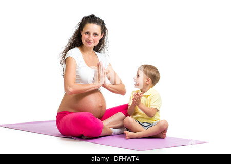 Pregnant woman relax doing yoga. Her son kid try to repeat exercises. Stock Photo