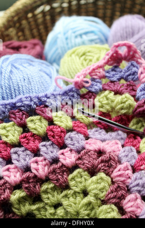 Crocheting an afghan blanket, crochet in a basket with pink , blue and green yarn Stock Photo