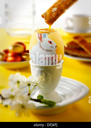 Traditional hand painted decorated boiled easter eggs in a breakfast setting with toast being dipped into the egg Stock Photo