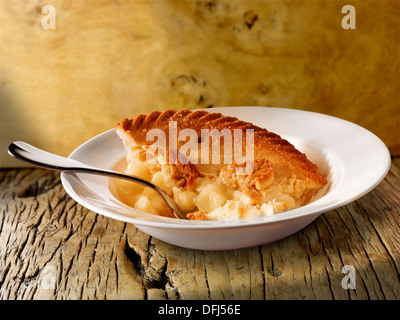 Traditional British apple pie and custard pudding served in a bowl on a wood table Stock Photo