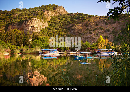 Boats on Dalyan «ay River with Lycian Rock Tombs in the cliffs . Mediterranean coast Turkey Stock Photo