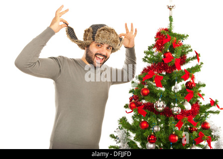Funny man wearing fur hat and standing near Xmas tree isolated on white background Stock Photo
