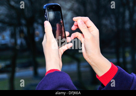 Youthful woman using smart phone in Central Park, New York City, USA Stock Photo