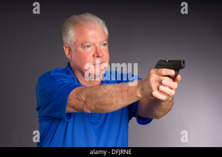 Man points small caliber semi automatic handgun to off camera right Stock Photo