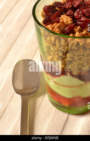 Healthy breakfast. Muesli with dried cranberries, yoghurt and cranberry juice. Served in green-tinted glass, beige tablecloth Stock Photo