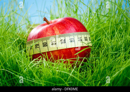 Red apple and measuring tape on the green grass. Stock Photo