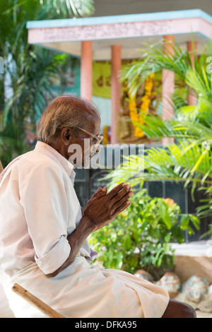 Indian man in prayer whilst waiting to be seen at Sri Sathya Sai Baba mobile outreach hospital. Andhra Pradesh, India Stock Photo